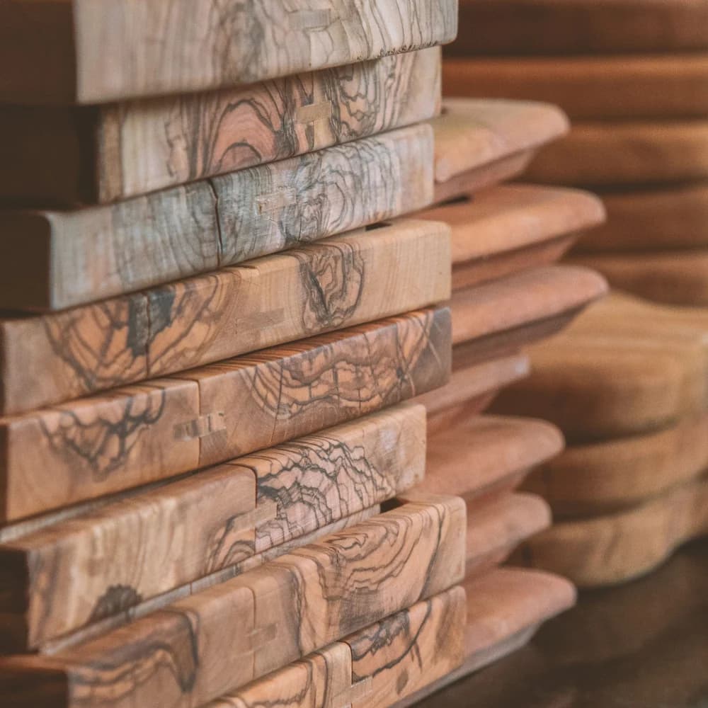 A single reclaimed olive-wood serving board standing on a wooden table