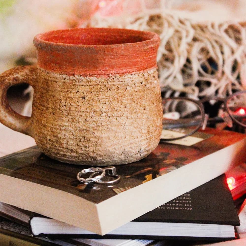 Two handmade salt-fired ceramic mugs standing side by side on a wooden table