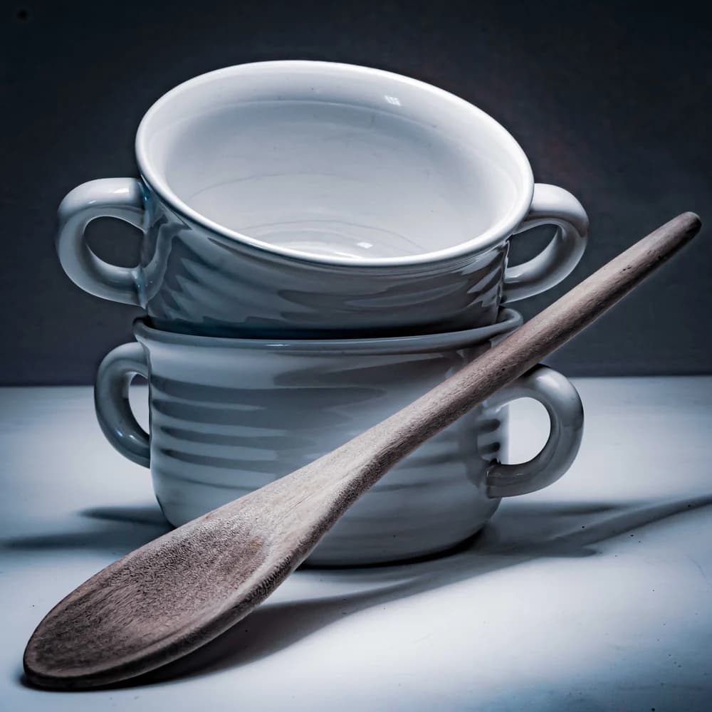 A stack of oatmeal-glazed stoneware bowls on a wooden surface